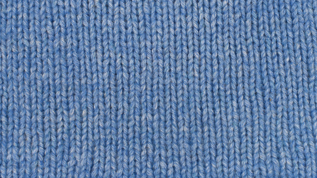 Knitted pattern as background. Blue knitted fabric texture. Hand knitting.