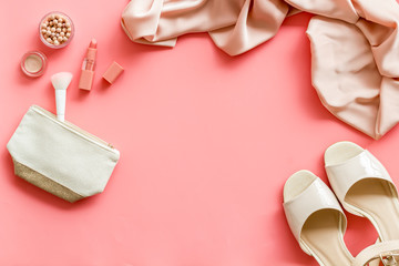 Fototapeta na wymiar Women fashion concept. Dress, shoes, cosmetics on pink background top-down frame copy space
