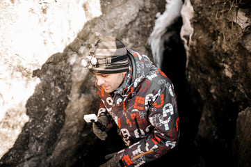a man with a headlamp leaves the cave in winter, underground cave studies and active sports tourism © Aleksandra