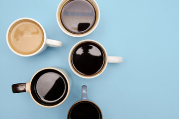 Many cups of different aromatic hot coffee on blue background, top view