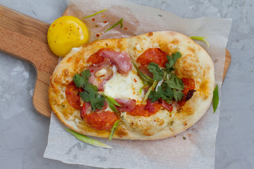 pizza with ingredients: dough, tuna, tomato sauce, egg and oregano. Small pizza with tomatoes, olives, mozzarella cheese and fresh Basil on a wooden Board, close-up. the concept of fast food.