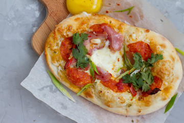 pizza with ingredients: dough, tuna, tomato sauce, egg and oregano. Small pizza with tomatoes, olives, mozzarella cheese and fresh Basil on a wooden Board, close-up. the concept of fast food.