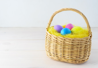 Easter eggs in a basket on a wooden table. Horizontal orientation, copy space.