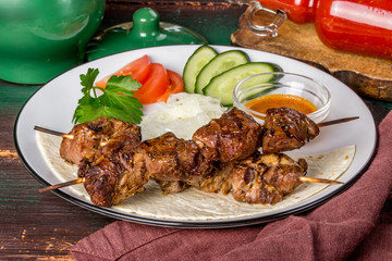 Lamb shish kebab with vegetables on a white plate