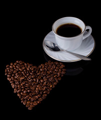 heart of roasted coffee beans and a Cup of black hot coffee on a black background with a copy of the space