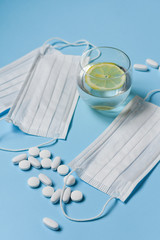 Pills and glass of water and  protective medical face mask on blue background top view . tools for...