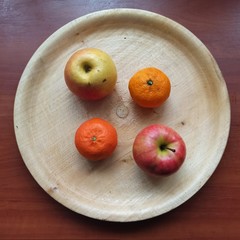 apples and mandarines on wooden tray on table