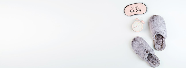 Flat lay with Soft fluffy slippers gray color and pink alarm clock isolated on white background. top view, overhead, mockup, template, copy space. Time for rest