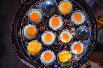 Obraz na płótnie Canvas Selective Focused Cooked Quail Eggs in heating mantle (indented frying pan). Traditional Thai Street Comfort Food, Asian Cuisine, Delicacy, Culture, Cooking, Snack, Indulgence and Nutrition concept