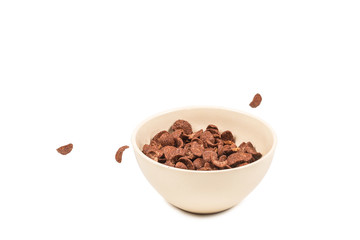 Chocolate corn flakes falling to the white bowl isolated on white. Motion.