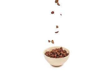 Chocolate corn flakes falling to the white bowl isolated on white. Motion.