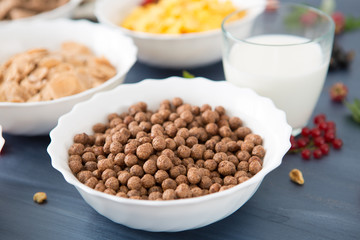 oatmeal with nuts and dried fruits on old white painted wooden table. Perfect breakfast Breakfast cereal mix: cornflakes, pads, muesli, multigrain flakes and chocolate balls