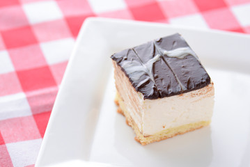 Chocolate souffle with thick chocolate ganache glaze served on a white plate on red plaid background