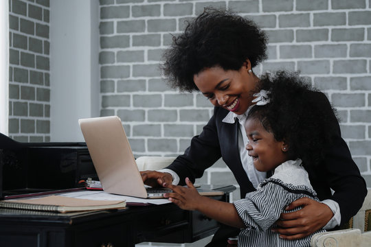 african american business woman taking care of her little daughter while working at home