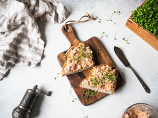 Healthy toasts with salmon pate and fresh green sprouts on yeast-free bread on wood cutting board...