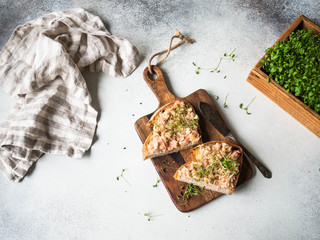 Healthy toasts with salmon pate and fresh green sprouts on yeast-free bread on wood cutting board...