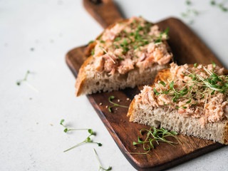 Healthy toasts with salmon pate and fresh green sprouts on yeast-free bread on wood cutting board...