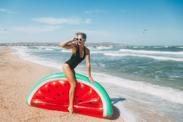 Naklejka na ściany i meble Slim girl playing with inflatable watermelon at sand beach