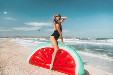 Naklejka na ściany i meble Slim girl playing with inflatable watermelon at sand beach