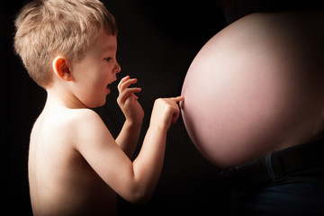 little boy, pressing mothers pregnant belly button 