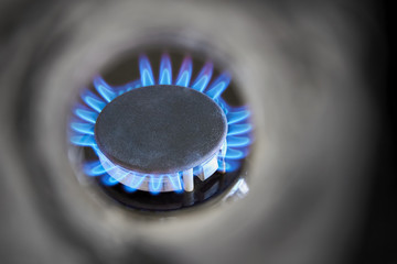 Look at a gas burner through an metal pipe. Burning blue gas. Concept of energy and its transportation. Closeup, selective focus