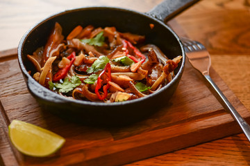 Pork ear snack in a pan. Spicy meat grilled pork served in a frying pan on rustic wooden cutting board.
