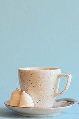 A cup of coffee latte or americano in a white cup isolated on light pastel blue background.