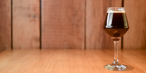 Glass of dark beer on light wooden background. Alcohol drink. Food photography concept, copy space.