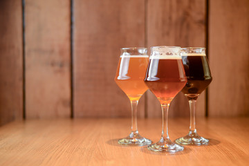 Three glasses with different beer on wooden table in a bar. Food photography concept, with copy space