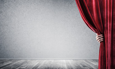 Concrete wall behind drapery curtain and hand opening it