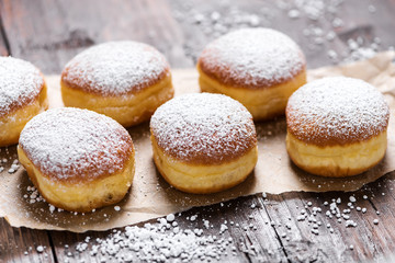 Close-up of donuts (Berlin pancakes) dusted with powdered sugar served on a rustic wooden table - 319646042