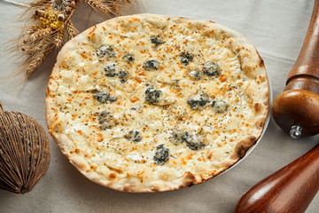 Close up view on Appetizing 4 cheese pizza with pear on a linen gray tablecloth in a restaurant. Pizza in composition. Italian cuisine. Food flat lay