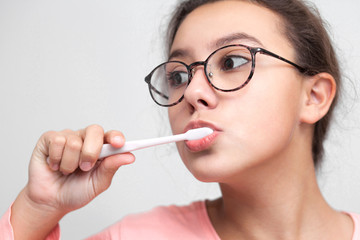 Teenage girl brushes her teeth. Close-up. On white background.