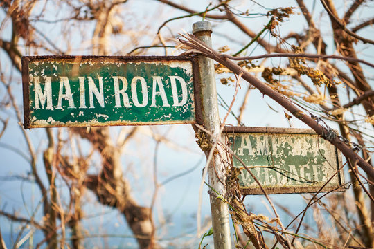 Almost unreadable rusty road signage 'Main Road', with branches and dry leafs hanging around, seen after typhoon Ursula on Boracay in the Philippines