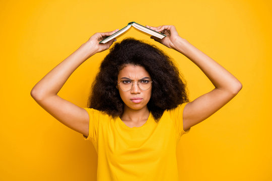 Close-up portrait of her she nice attractive lovely gloomy grumpy wavy-haired girl holding book over head isolated over bright vivid shine vibrant yellow color background