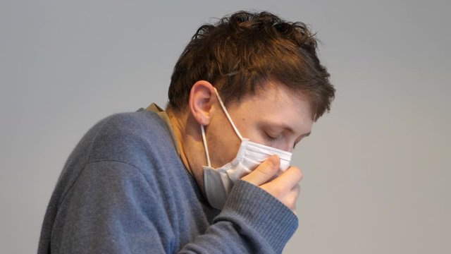 A man with the flu virus coughing while wearing a surgical mask