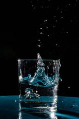 Multicolored splashes of summer. Fresh fruit and splashes of water.The photo shows a slice of green apple thrown into a glass of water. Splashes of cool drink refresh.