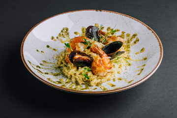 Prawn orzotto with mussels and pesto on a black background