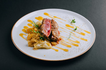 Duck breast fillet with quinoa garnish with young pea sprouts on a black background