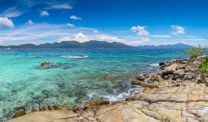 sea view panorama of arch rocks and tourists in blue-green sea with blue sky background, Ko Rokroy, Tarutao National Park, Satun, southern of Thailand.