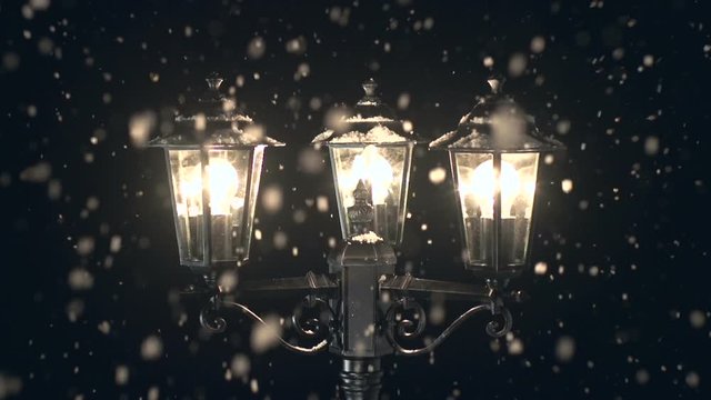Lamppost at Christmas and it's snowing. The snow falls outside at night. Festive