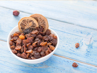 dried fruits in a white plate on a blue wooden background.