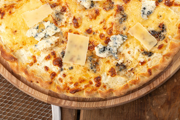 Delicious fresh pizza on table. Delicious pizza Four Cheeses with cheddar, Parmesan, mozzarella and tomato sauce. Homemade delicious italian pizza on wooden table for dinner. Italian cuisine.