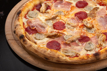 Delicious fresh pizza on table.  Delicious pizza. Large meat pizza with bacon, sausage, salami, pepperoni and olives. Homemade delicious italian pizza on wooden table for dinner. Italian cuisine.