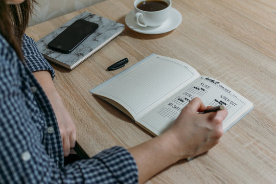 Bullet Journal Habit Tracker. Woman cross off day with routine in her Habit Tracker. Selective focus