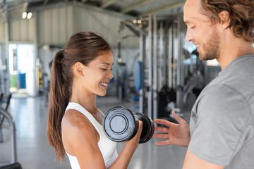 Gordijnen Gym workout personal trainer man helping woman having the right body posture to lift dumbbell weights. Exercise fit lifestyle. © Maridav