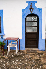 Fototapeta na wymiar Colorful blue wall facade, door, and table and chairs in the small village of Alte, Portugal