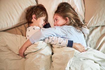 Bruder und Schwester kuscheln im Bett