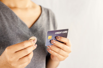 shopaholic Asian woman over spending on credit card hand holding one coin 