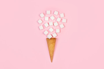 Terrones de azúcar blanco con cono de oblea sobre fondo rosa liso aislado. Vista superior. Copy space